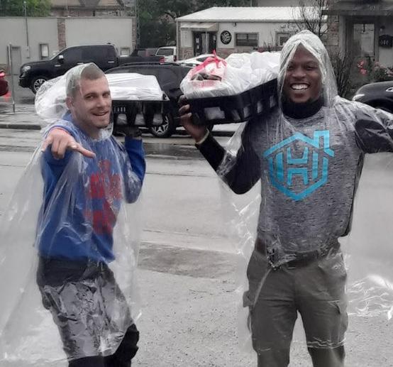 Two men carrying bagged donations to a waiting car.